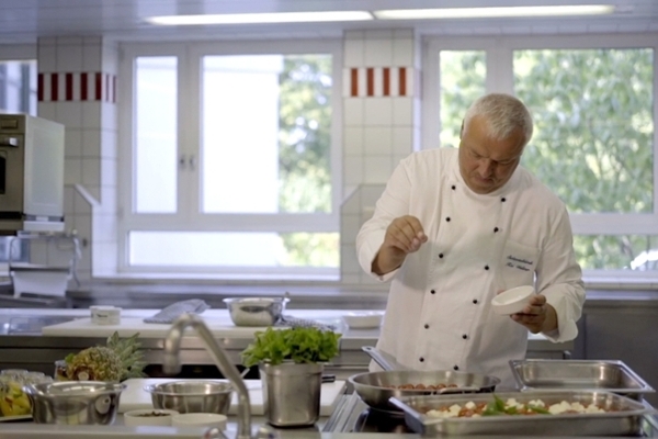 Ein Koch würzt das Essen Ein Koch würzt das Essen